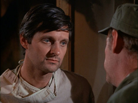 Screenshot of Alan Alda as Hawkeye Pierce, looking sad and facing Colonel Blake