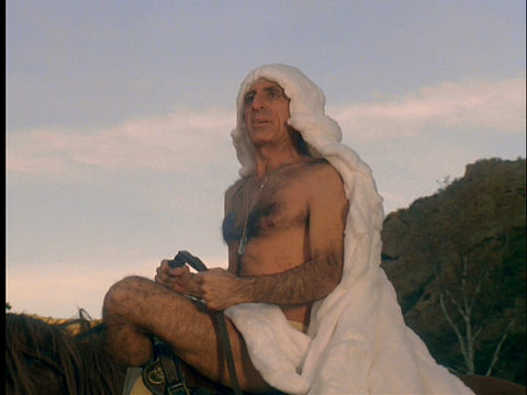 Image of Klinger, atop Sophie the horse, wearing nothing but a white sheet