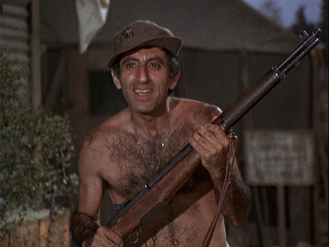 Klinger naked holding a rifle