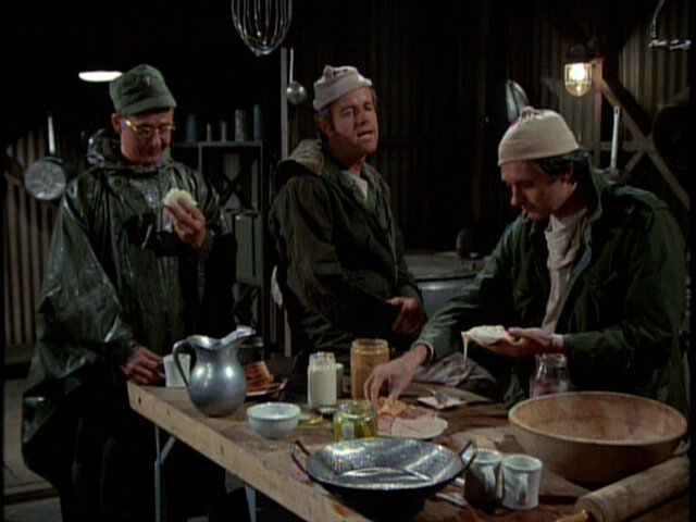 Still from the M*A*S*H episode Deluge showing Father Mulcahy, B.J. and Hawkeye in the kitchen.
