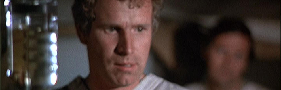 A sinister looking Trapper staring at wounded prisoner, Hawkeye in the background