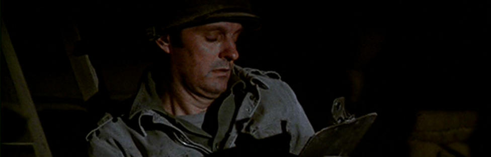 Hawkeye writing his will in the dark, under a table